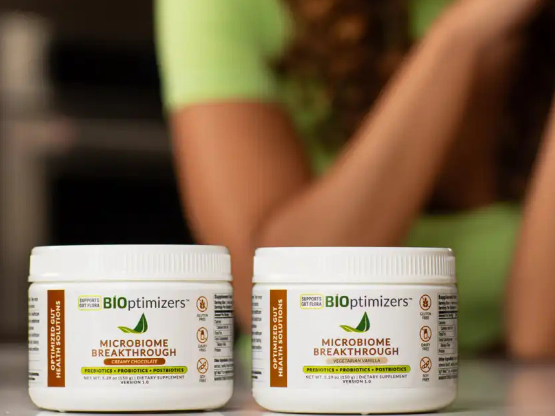 Two BiOptimizers Microbiome Breakthrough tubs—Creamy Chocolate and Vegetarian Vanilla—on a kitchen counter.